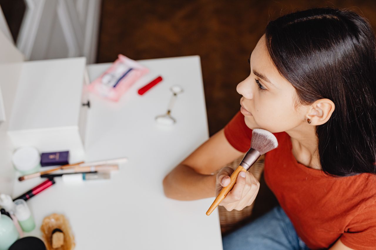 Home Top view of a woman applying makeup with a brush at a vanity table.